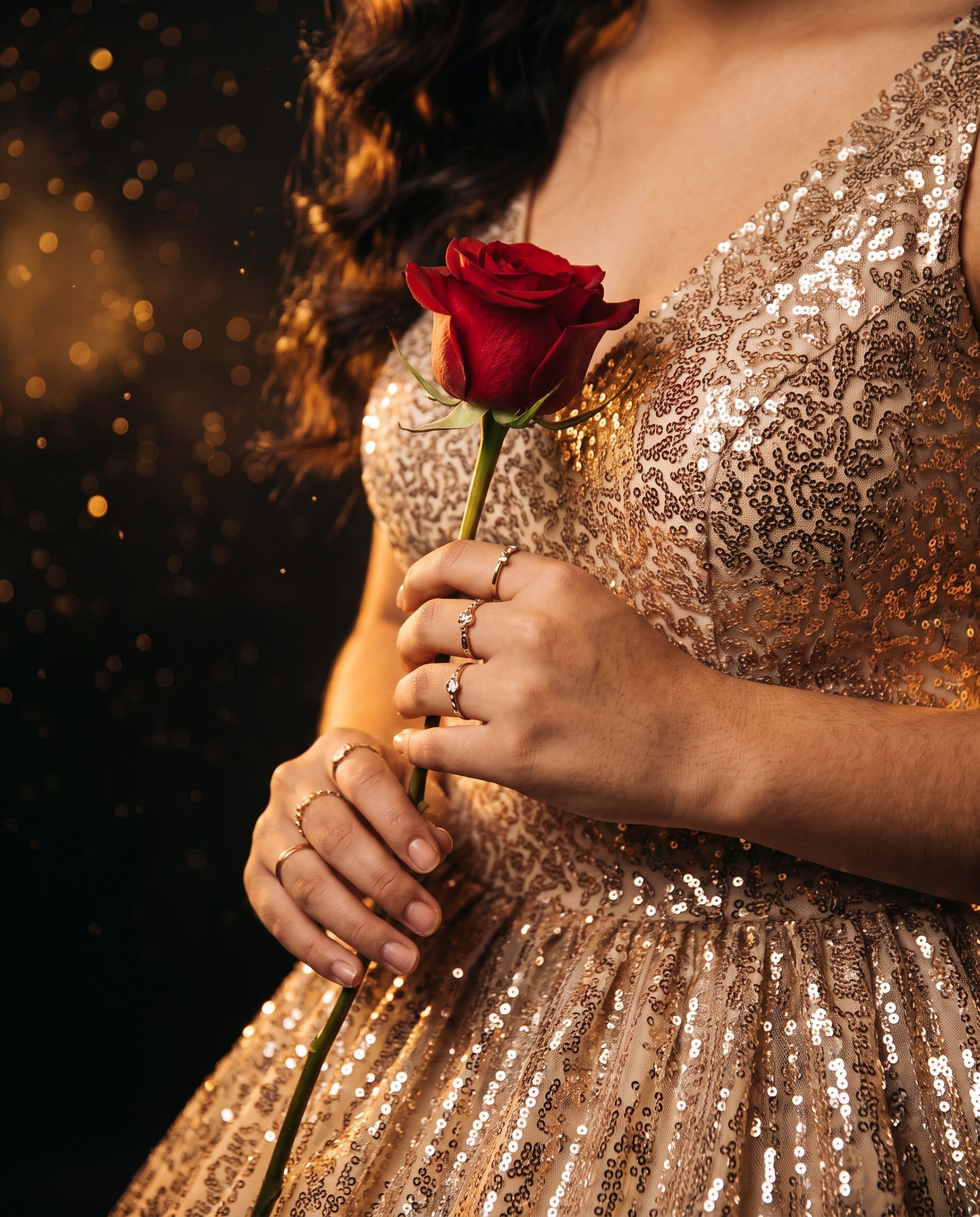 Manos de Daniela con una rosa roja sobre el vestido dorado