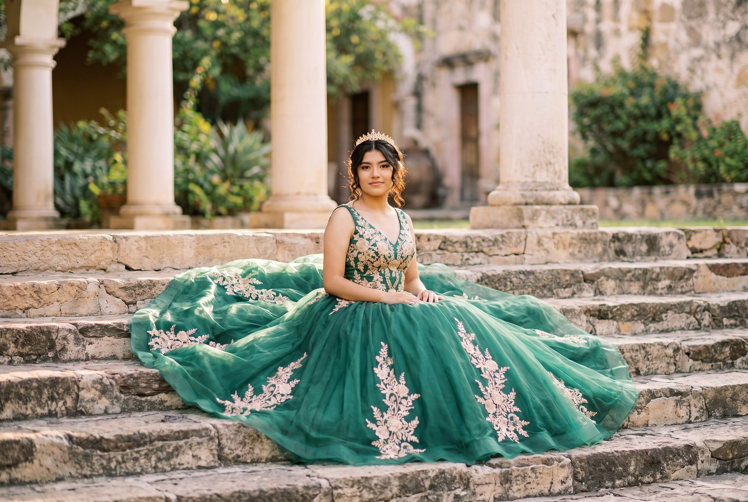 Valeria sentada en una escalinata de piedra con el vestido extendido