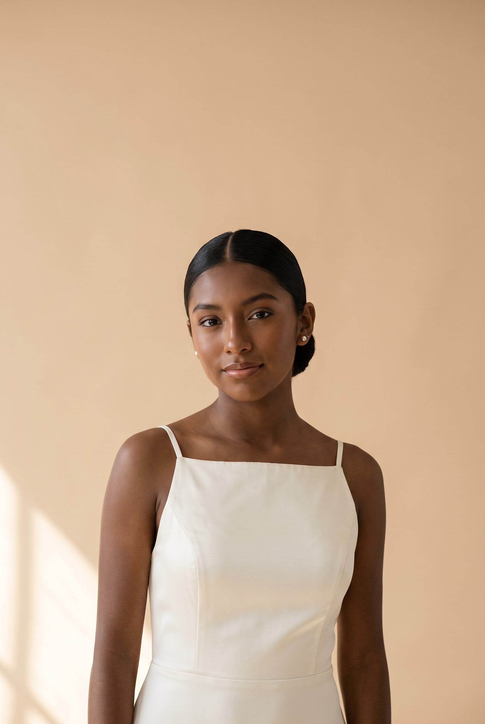 Renata con vestido de satín marfil frente a un fondo color arena